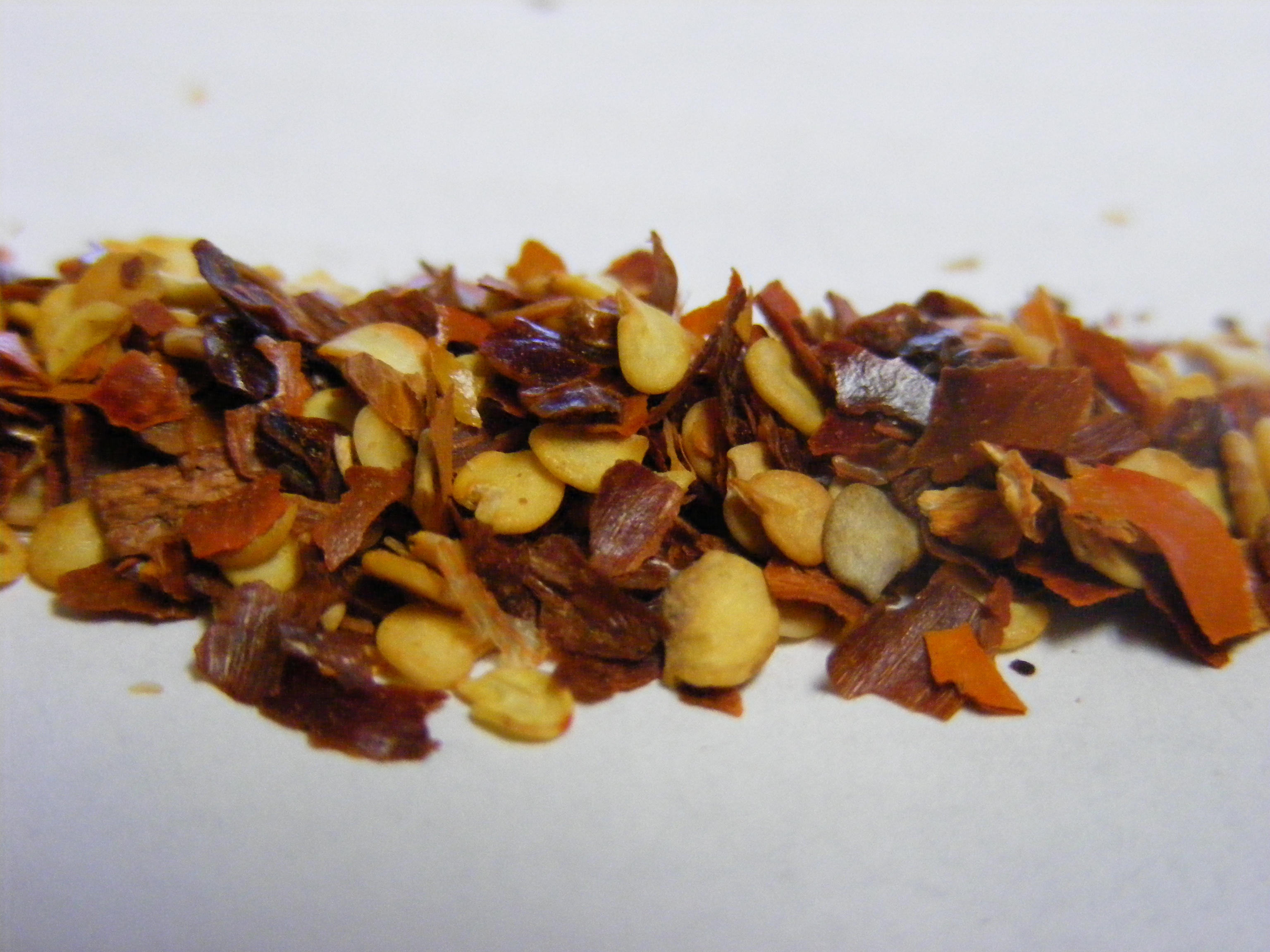 Coarse crushed red chilli flakes with visible golden seeds for seasoning